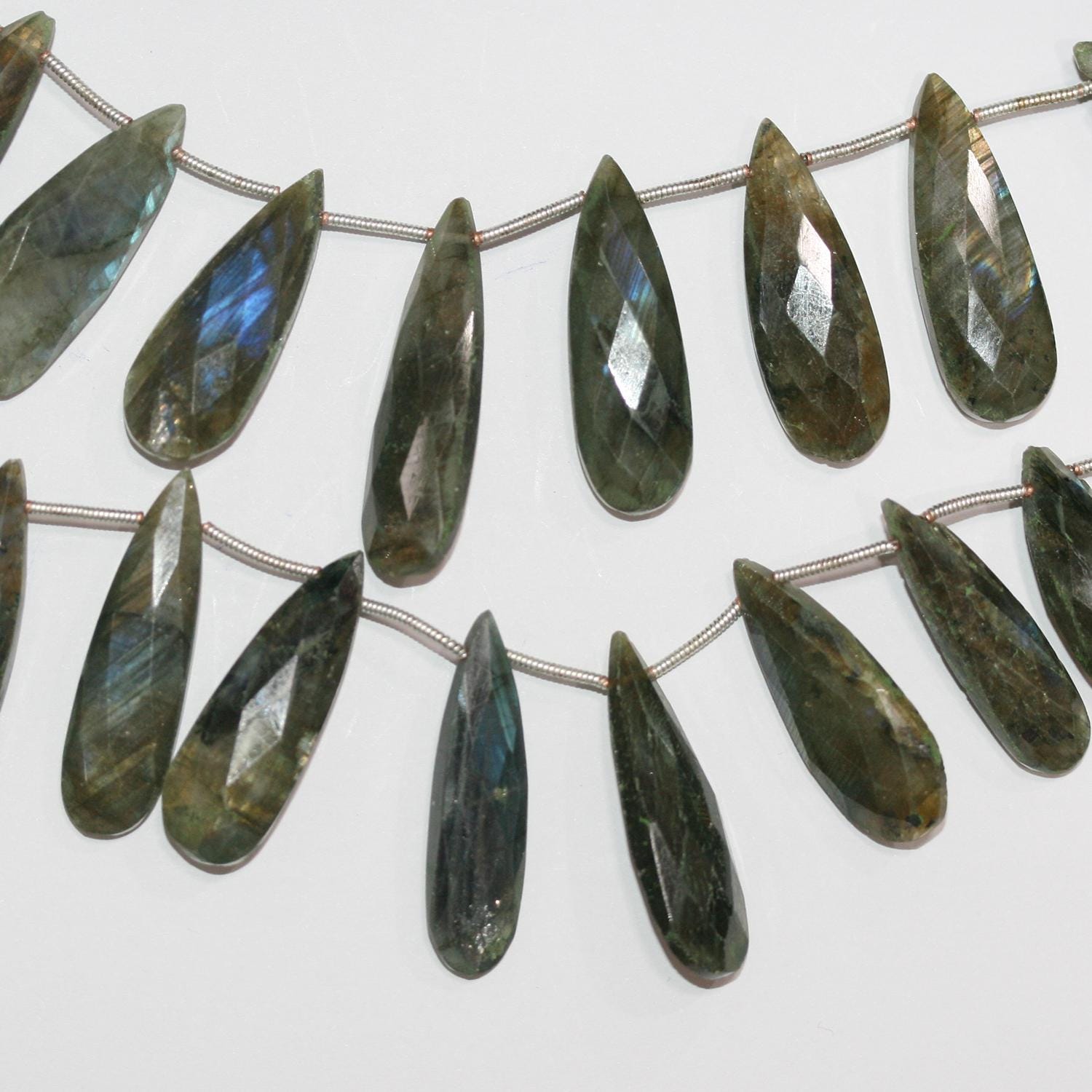 Perles en forme de goutte à facettes dégradées en Labradorite de 21 x 10 à 30 x 10 mm. Longueur du fil : environ 21 cm.