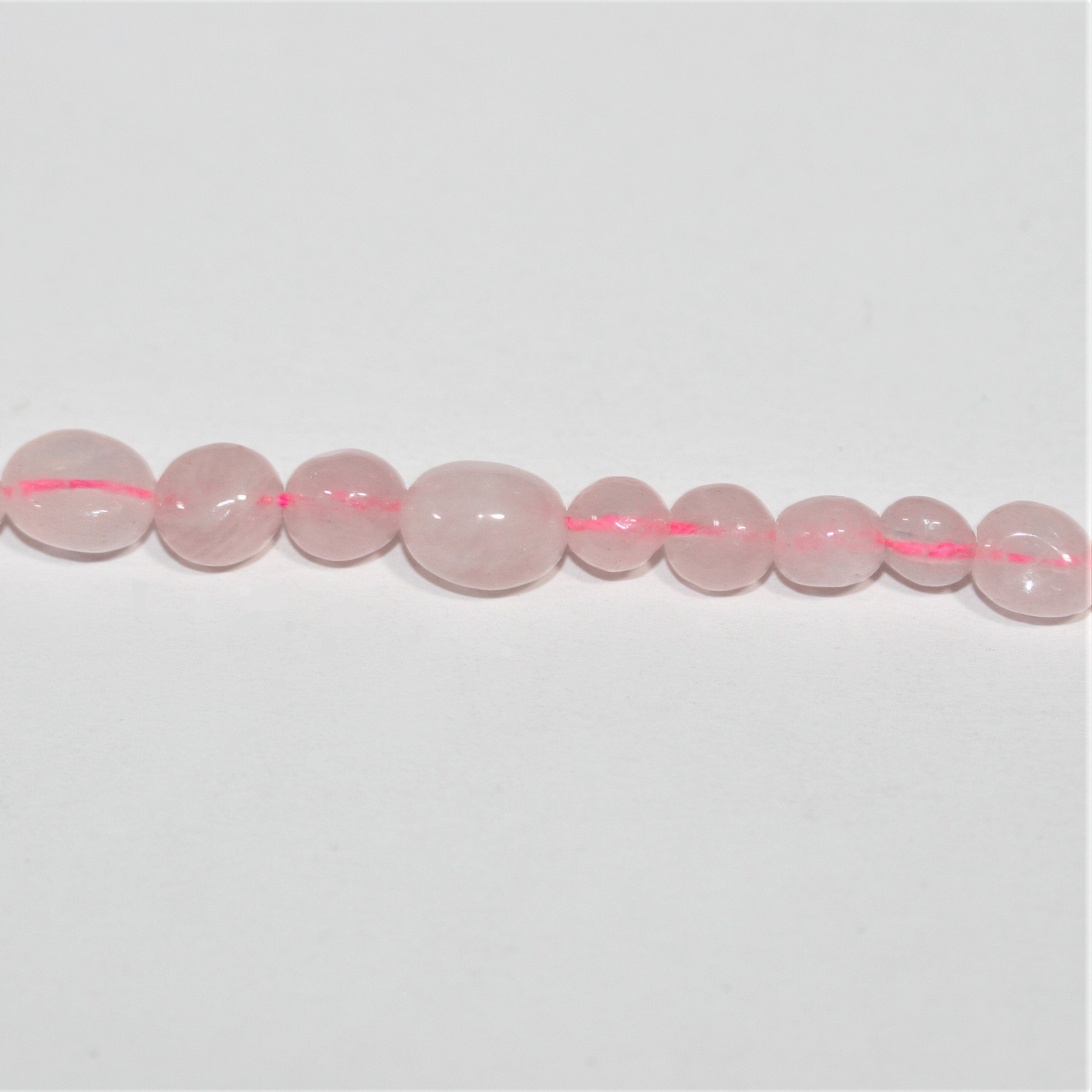 Perles de quartz rose St. Rose lisses en pépites de 15 pouces (6-8 mm). Longueur approximative du brin : 39 cm.