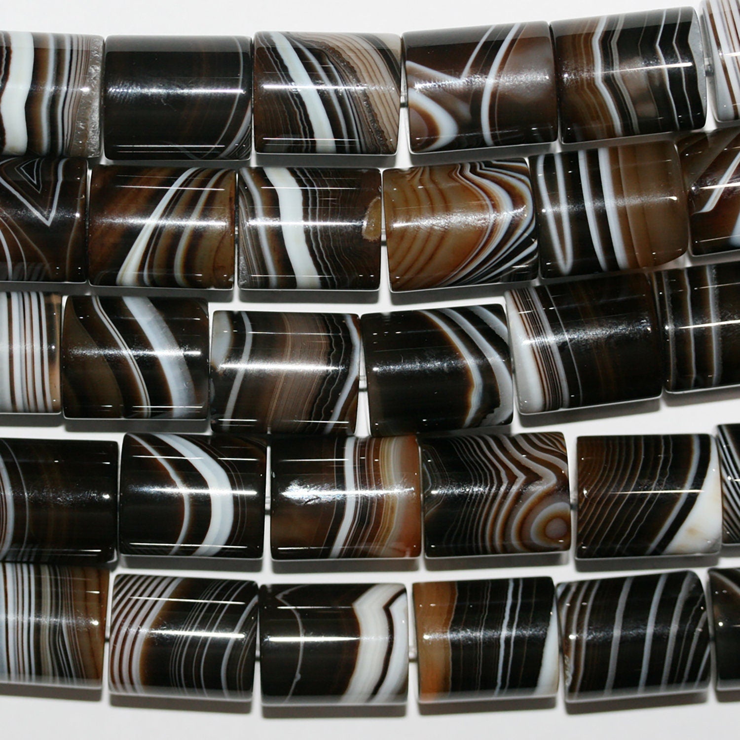 Perles cylindriques lisses en agate à rayures brunes, 17 x 15 mm environ. Longueur du fil : 39 cm.