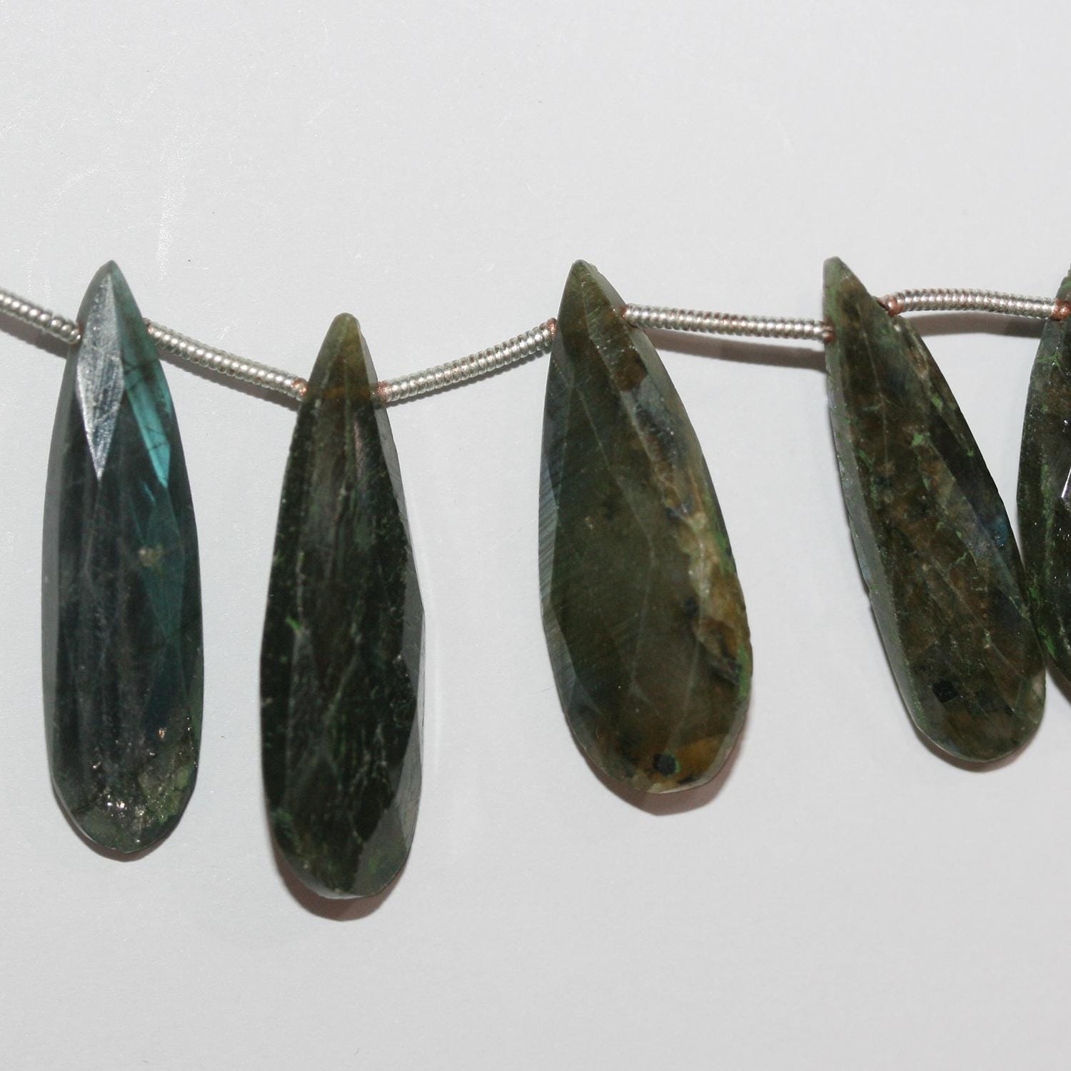 Perles en forme de goutte à facettes dégradées en Labradorite de 21 x 10 à 30 x 10 mm. Longueur du fil : environ 21 cm.