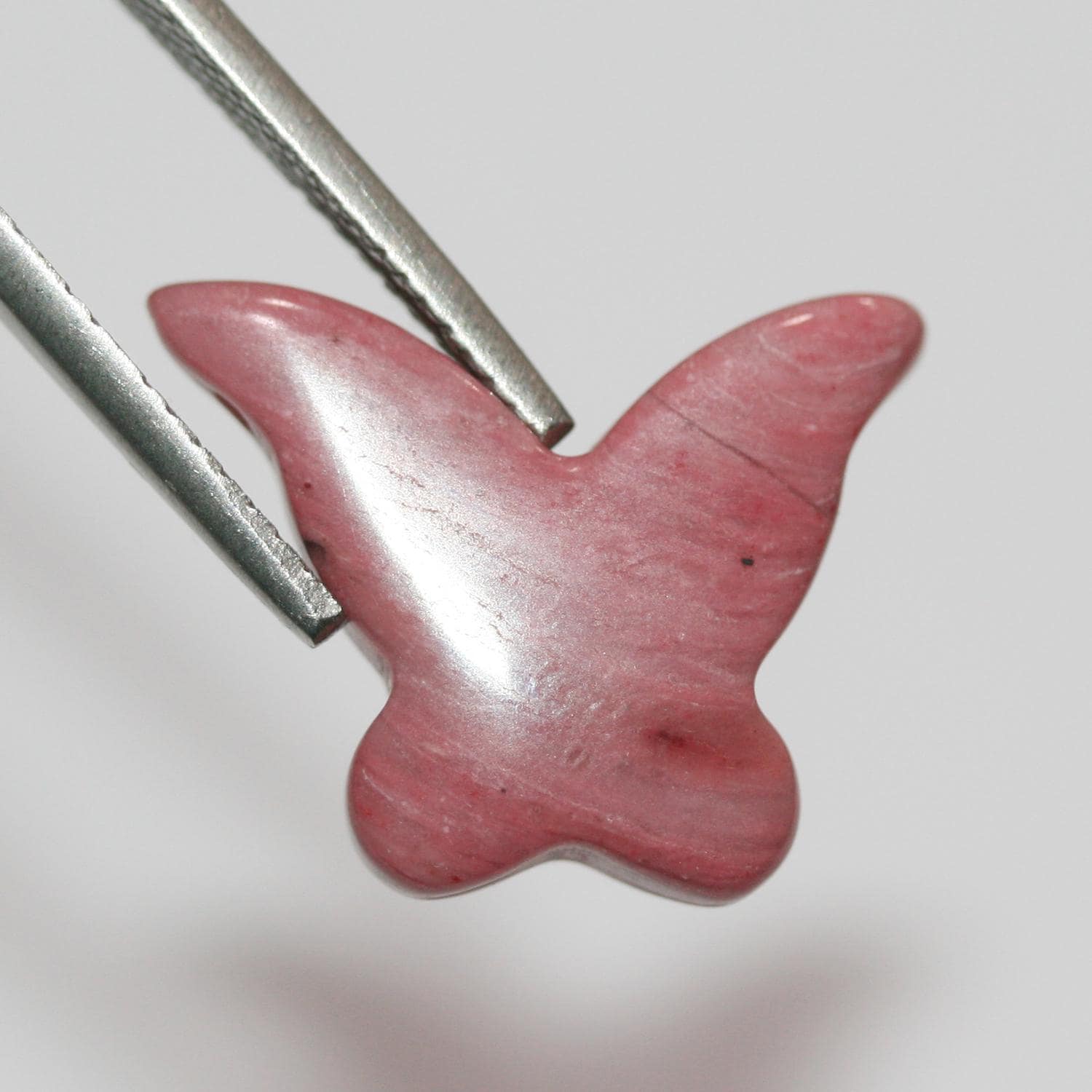Pendentif papillon lisse en rhodonite, 16 x 20 mm environ.