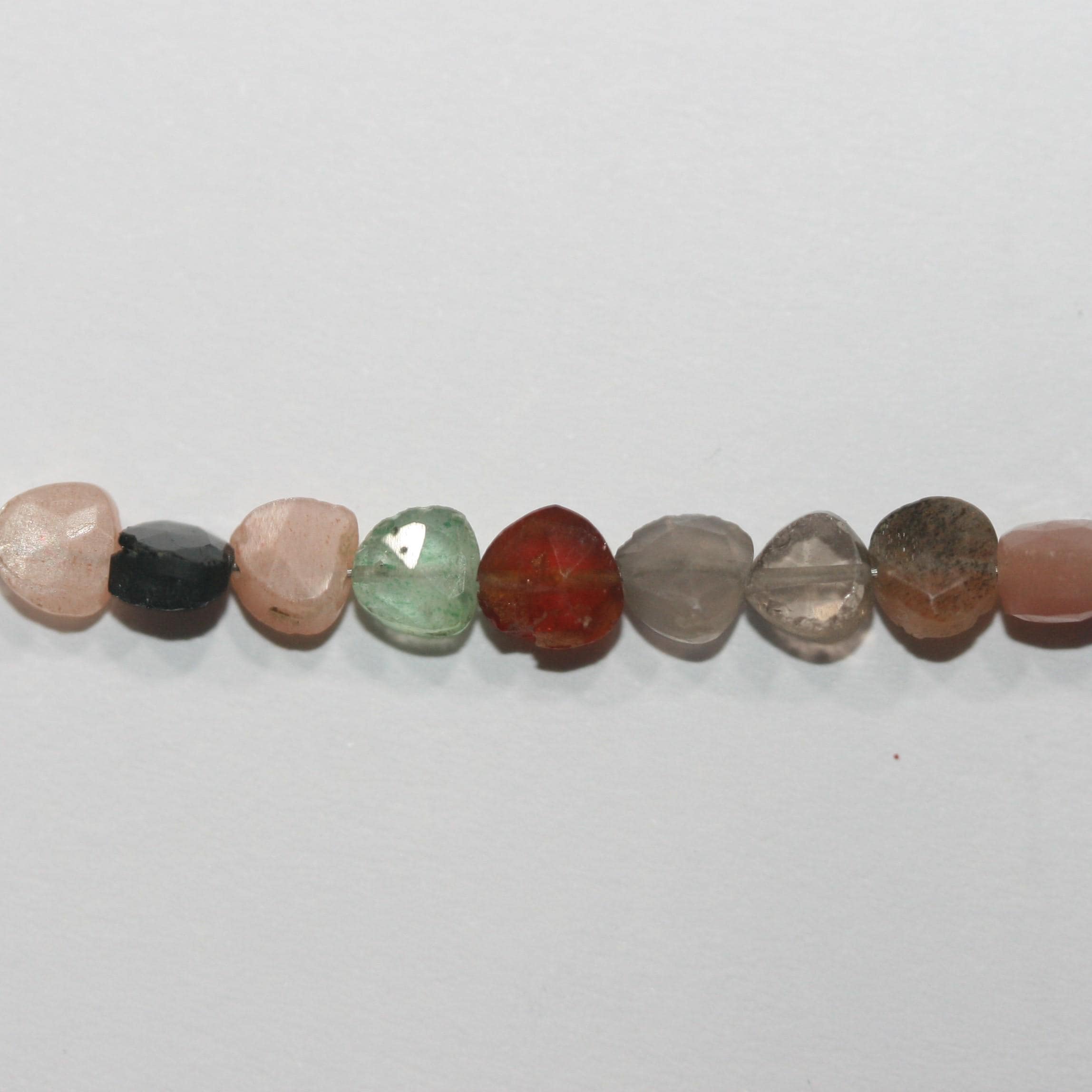 Perles en forme de cœur, serties de pierres multicolores, de 8 à 10 mm environ. Longueur du fil : 20 cm. Réf. 15010