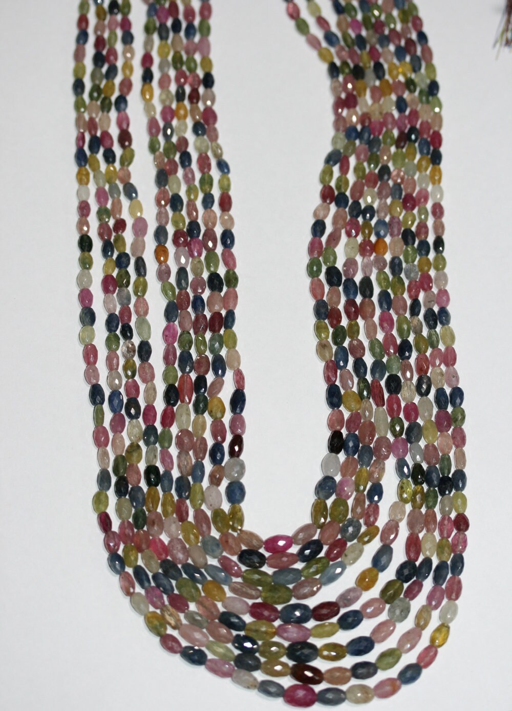Collier de perles facettées en saphir multicolore (9 rangs), de forme cylindrique, de dimensions approximatives 6x4-10x6 mm.