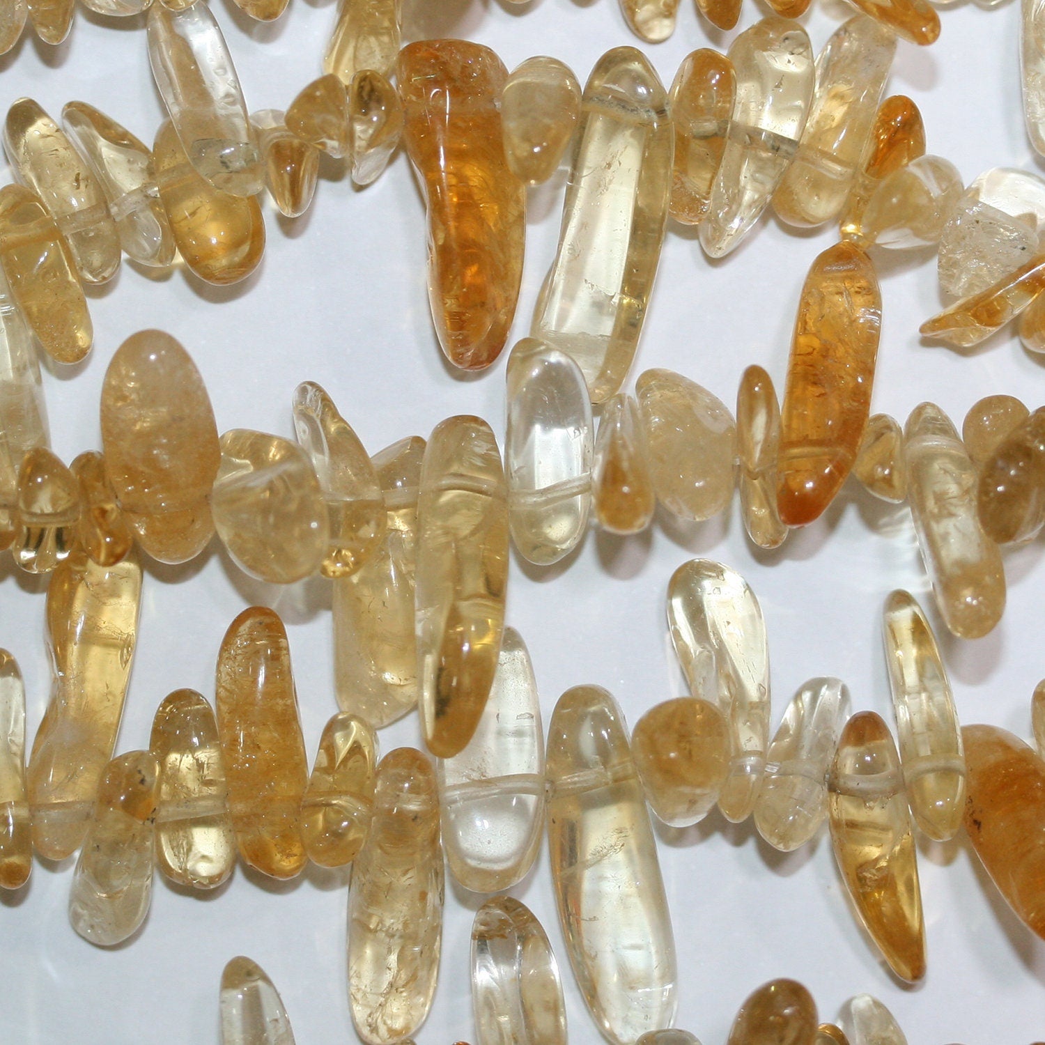 Perles de citrine St. Citrine lisses et irrégulières de 15 à 20 mm. Longueur approximative du fil : 39 cm.