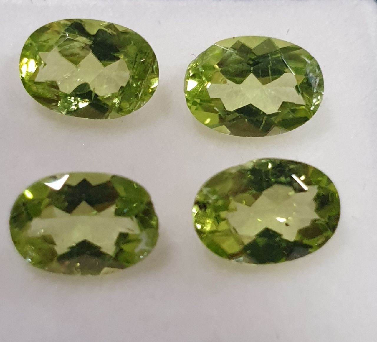 Lote de 4 peridotos de corte ovalado facetado de 7 x 5 mm, color verde olivino.