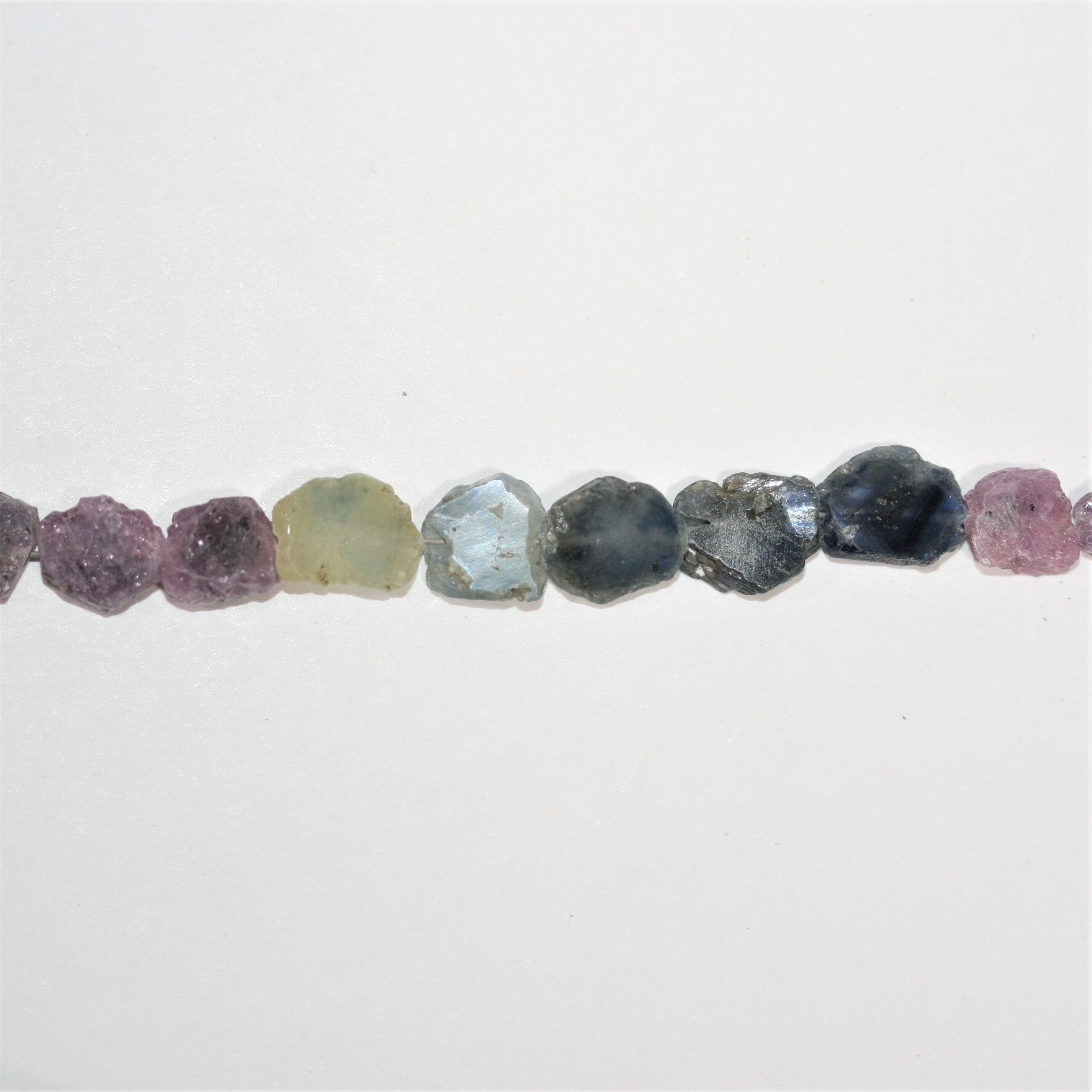 Perles ovales lisses et irrégulières en saphirs multicolores, de 6 à 8 mm environ. Longueur du fil : 40 cm environ.