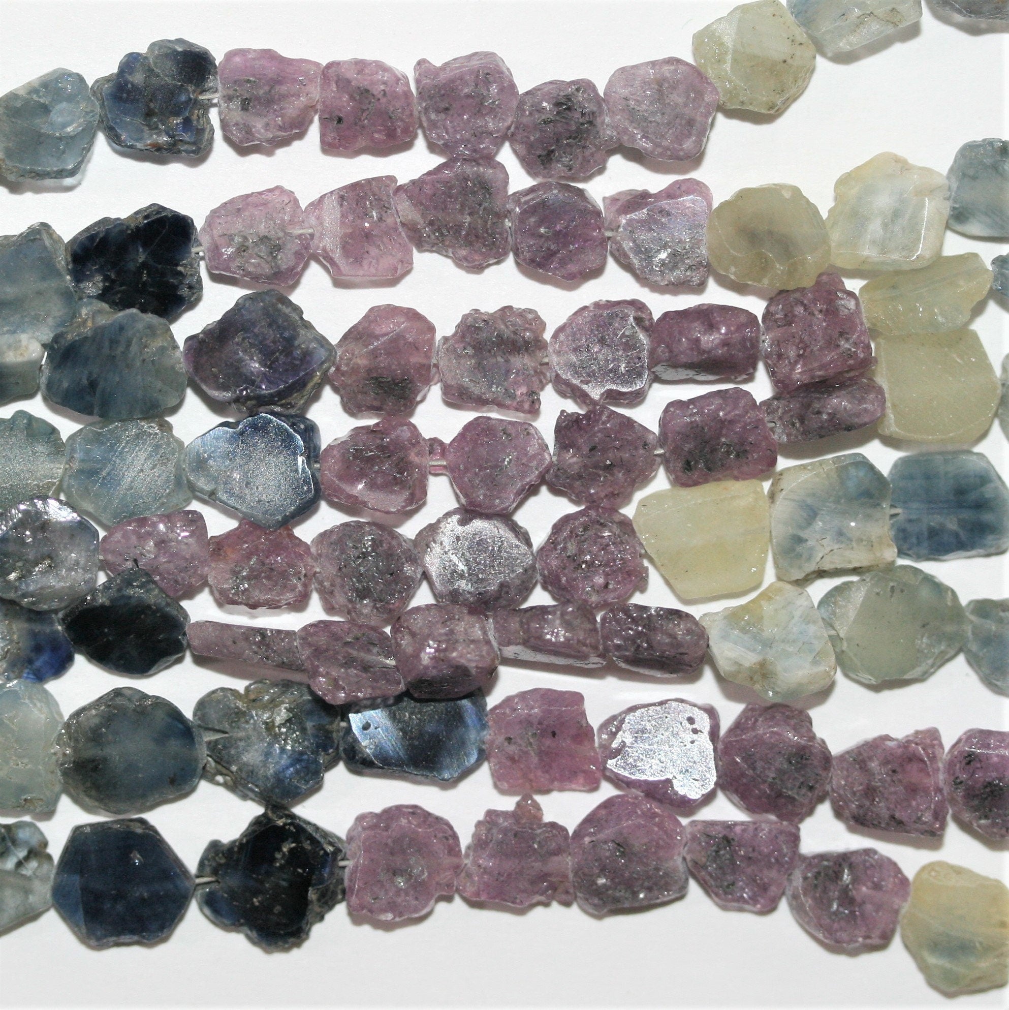 Perles ovales lisses et irrégulières en saphirs multicolores, de 6 à 8 mm environ. Longueur du fil : 40 cm environ.