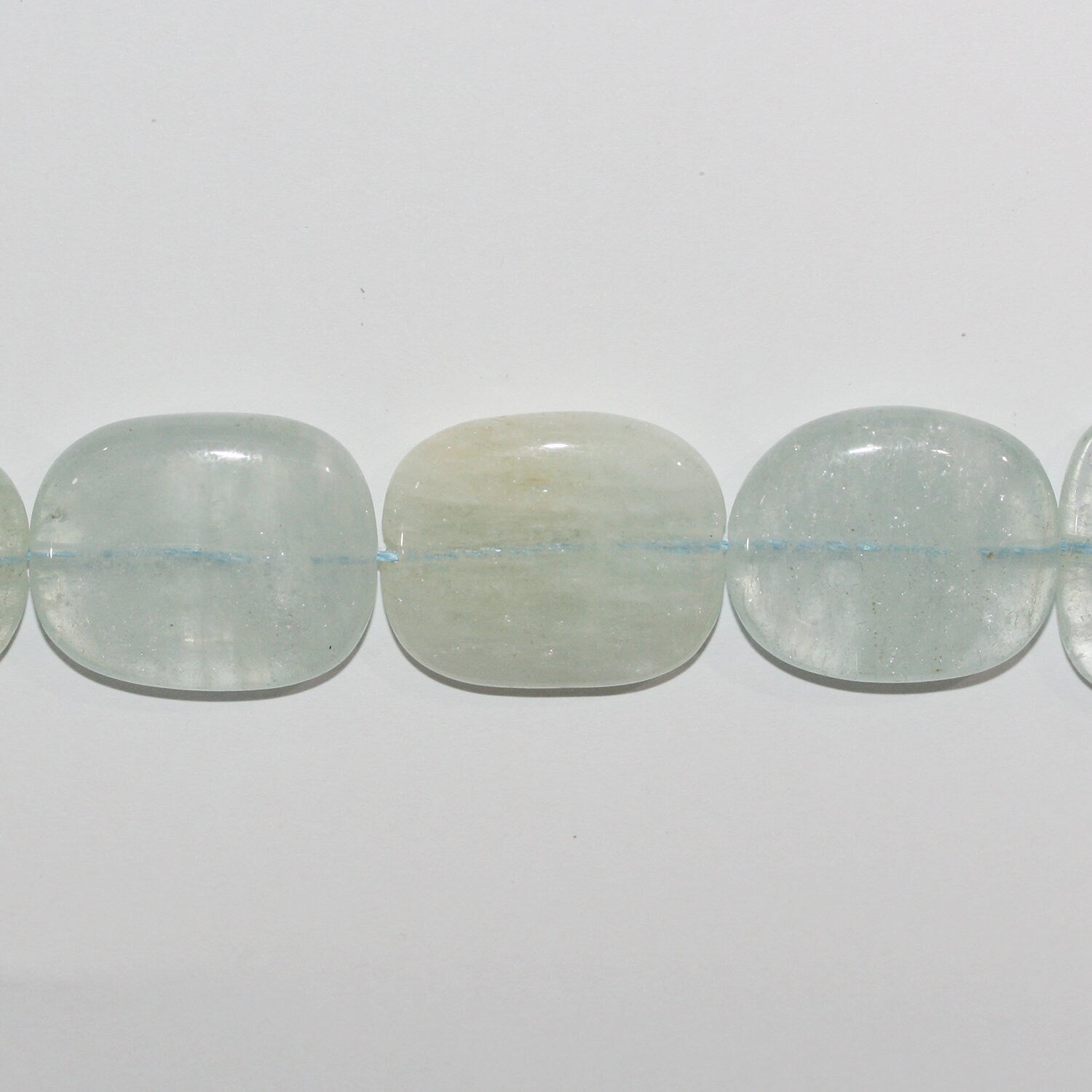 Perles ovales lisses plates en aigue-marine de 15 pouces (27 x 23 mm). Longueur approximative du brin : 39 cm.