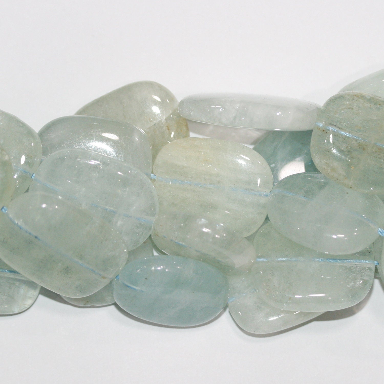 Perles ovales lisses plates en aigue-marine de 15 pouces (27 x 23 mm). Longueur approximative du brin : 39 cm.